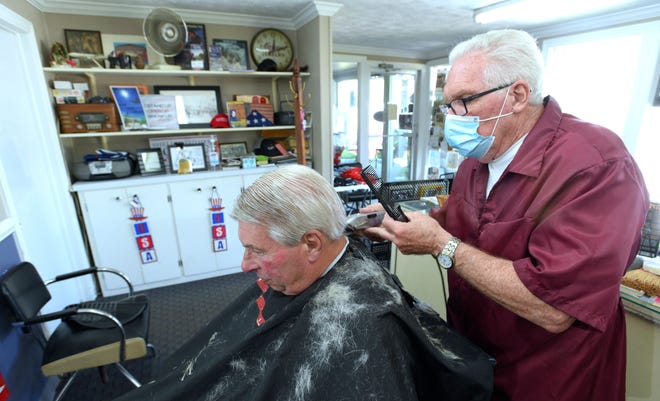 Karl Manke, right, cuts the hair of client Mike Calhoun, of Owosso.