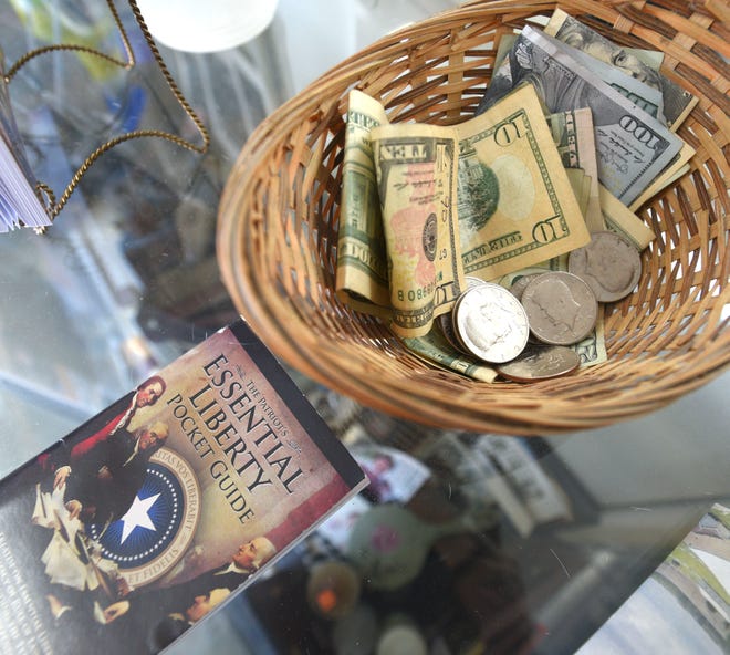 Older Kennedy half dollars are part of a tip from a client as the money basket rests near ' The Patriot ' s Essential Liberty Pocket Guide. ' The guide is ' devoted to the restoration of rule of law as enshrined in our Constitution. '