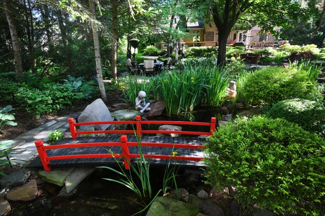 A red bridge, often found in Japanese gardens, crosses a stream. Red bridges symbolize wisdom and transformation.