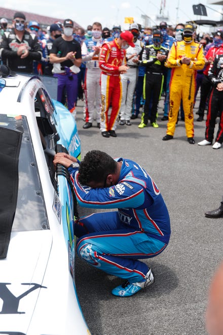 Driver Bubba Wallace, front, is overcome with emotion as he arrives at his car in the pits.