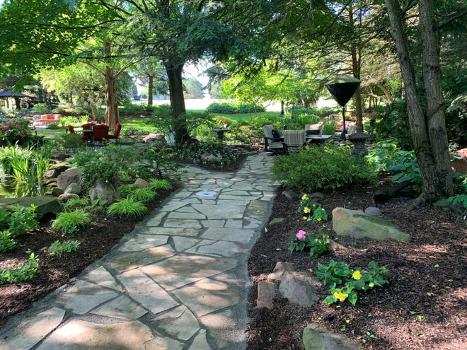 A firepit with seating sits on one side of the flagstone path while another seating area sits on the other.