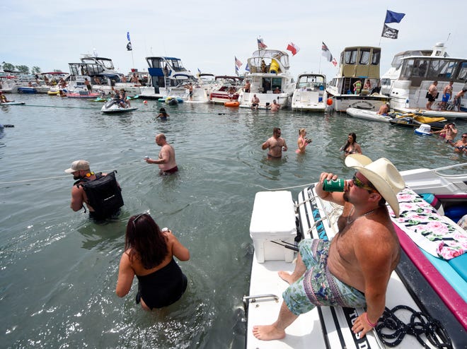 Scott Leuenberger, Bay City, has a drink on the back of a boat during the annual Jobbie Nooner at Gull Island on Lake St. Clair, Friday, June 26, 2020.