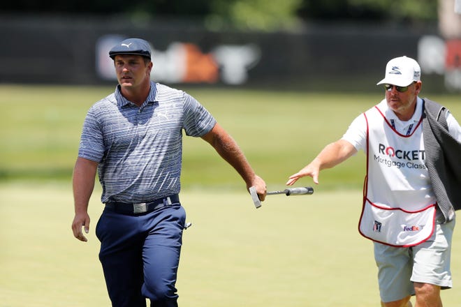 Bryson DeChambeau passes his putter to his caddie after playing the first hole.