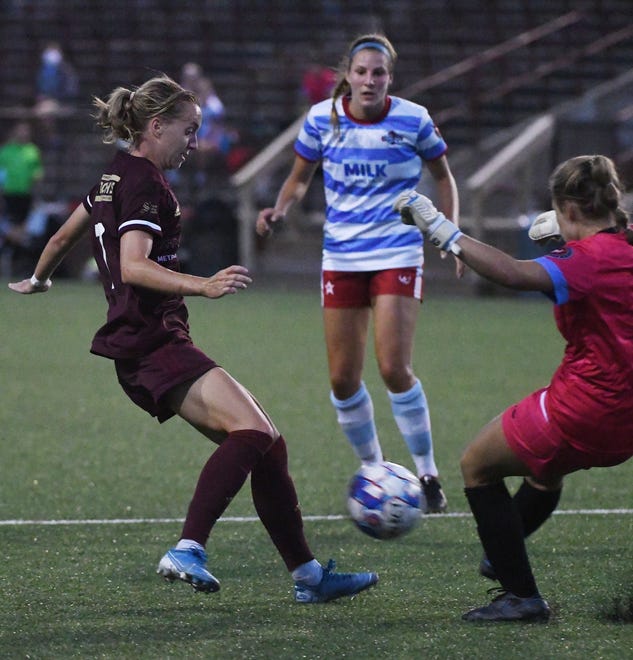 Detroit City FC's Sydney Blomquist taps the ball past Lansing United goalie Samantha Tracey to teammate Kenna White, who put in the winning goal late in the second half.