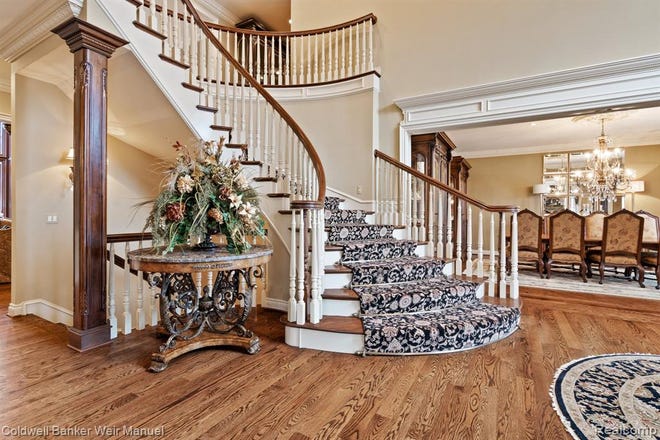 A winding staircase leads up to three large en suites with decorative molding and views of the surrounding area.