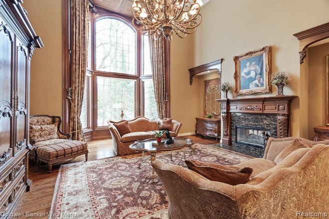 One of the living spaces with hardwood floors, a motorized chandelier, extra large windows and fireplace.