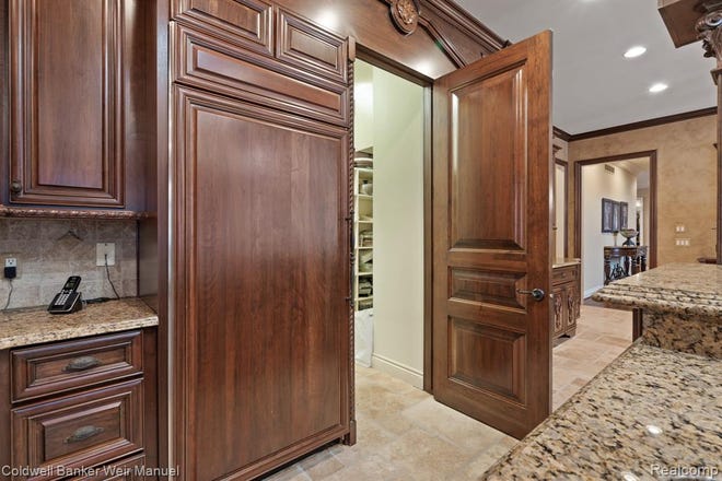 Tuscan designed chef's kitchen with granite and high-end appliances and cabinetry with a door to the pantry.
