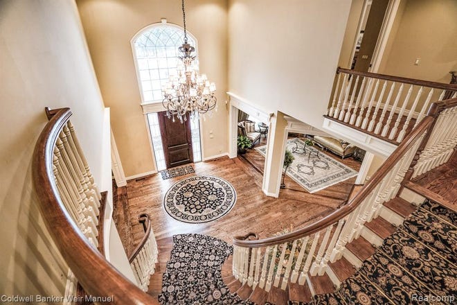 A winding staircase leads up to three large en suites with decorative molding and views of the surrounding area.