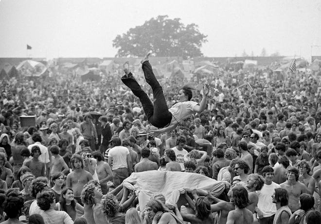 As concert goers wait for the rock music to begin, a group takes part in a blanket toss at the Goose Lake International Music Festival near Jackson, Mich., Aug. 9, 1970. Here a young woman gets tossed in the air. The crowd, numbering around 200,000, seemed to enjoy the three-day event which was free of incident.