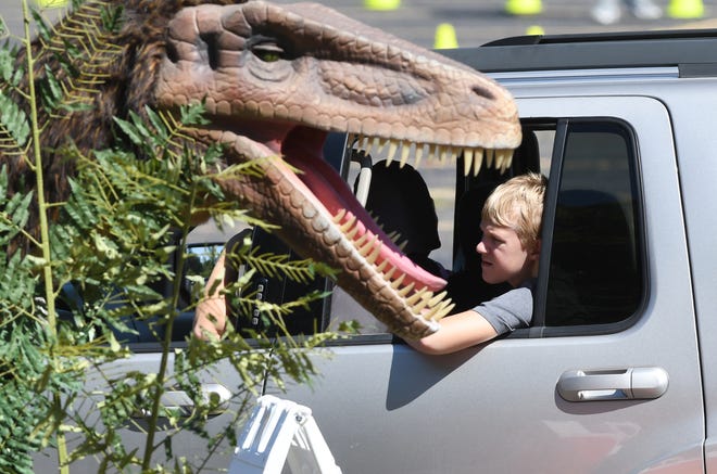 Children watch dinosaurs at Jurassic Quest, a touring dinosaur exhibit, has been transformed into an interactive drive-thru experience art DTE Energy Music Theatre in Clarkston on Friday, August 7, 2020.