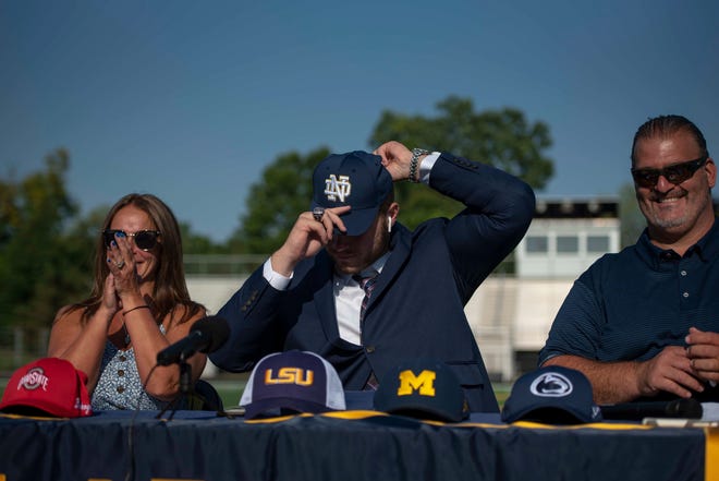 Rocco Spindler puts on a Notre Dame hat on after declaring his commitment to Notre Dame during his college decision choice at Clarkston High School in Clarkston on Aug. 8, 2020.