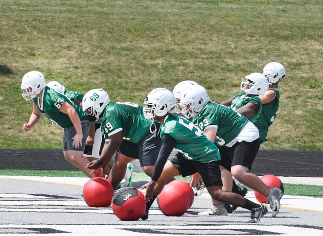 Members of the West Bloomfield football team offensive line get low, running against resistance bands and rolling weighted balls during practice Monday, Aug. 10, 2020, in West Bloomfield, Michigan.