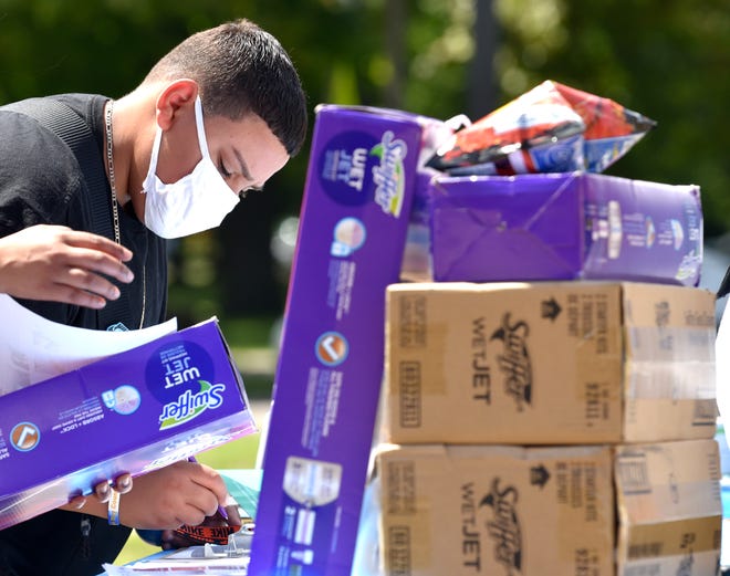 Andres Gonzalez, 14, of Detroit, who will be a freshman at Western High School signs up and receives a Swiffer Wet Jet.