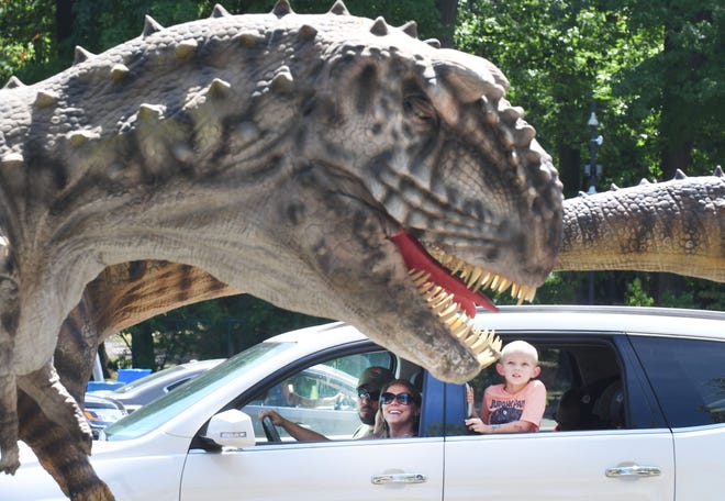 April Petz and Quentin Petz, 5 get up close and personal with a large dinosaur as they explore Jurassic Quest in the parking lot at DTE Energy Music Theatre.