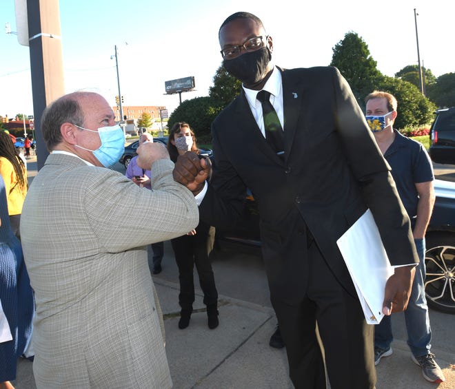 Mayor Mike Duggan, left, and Lt. Gov. Garlin Gilchrist fist bump upon Gilchrist ' s arrival before they address the media and family member participate in the Memorial Drive on Belle Isle to Honor COVID-19 Victims and Commemorate Detroit ' s Resiliency, Monday morning, Aug. 31, 2020