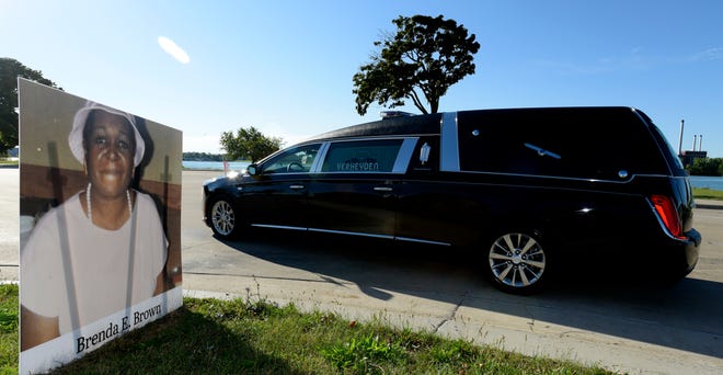This Verheyden hearse leads one of the 15 processions as they pass the portrait of COVID-19 victim Brenda E. Brown.
