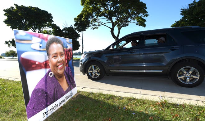 This vehicle passes the portrait of COVID-19 victim Patricia Ann Brooks.