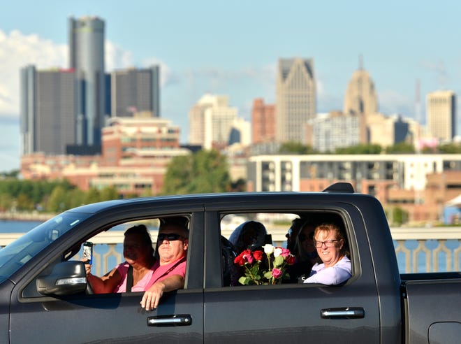 Family members of COVID-19 victim Alyssa Calcaterra of Madison Heights wait in the procession line on the Douglas MacArthur Bridge in front the skyline of Detroit.