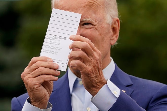 Democratic presidential candidate former Vice President Joe Biden displays a card he carries showing daily updates on American troop casualties and coronavirus infections as he speaks during a campaign event on manufacturing and buying American-made products at UAW Region 1 headquarters in Warren.