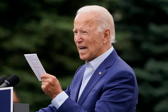 Democratic presidential candidate former Vice President Joe Biden reads from a card he carries showing daily updates on American troop casualties and coronavirus infections as he speaks during a campaign event on manufacturing and buying American-made products at UAW Region 1 headquarters in Warren, Mich., Wednesday, Sept. 9, 2020.