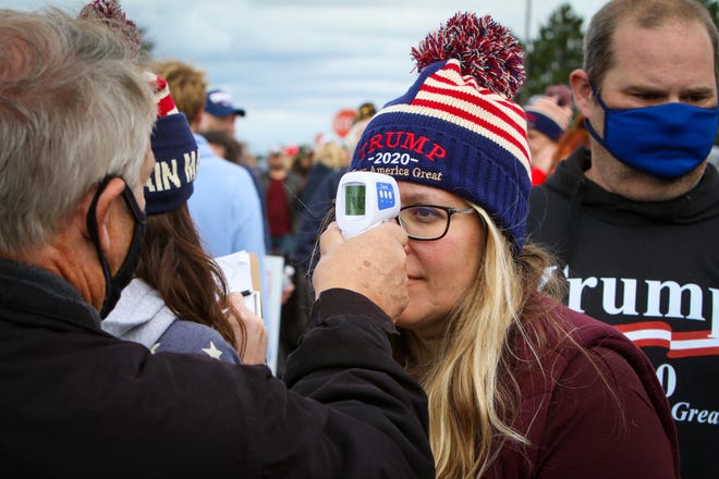 Bethany Burns of Bay City gets her temperature checked prior to entering the rally by Tom Krzeszewski of Swan Creek Township.  President Donald Trump makes a campaign stop at an airplane hangar in Freeland, Michigan on Thursday, September 10, 2020.