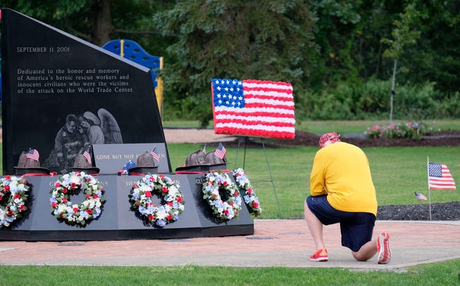 A man kneels at the Washingtonville Firefighters World Trade Center Memorial on the 19th anniversary of the 9/11 terror attacks Friday, Sept. 11, 2020, in Washingtonville, N.Y.