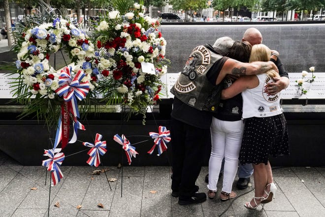 Mourners hug beside the names of the deceased Jesus Sanchez and Marianne MacFarlane at the National September 11 Memorial and Museum, Friday, Sept. 11, 2020, in New York. Americans commemorated 9/11 with tributes that have been altered by coronavirus precautions and woven into the presidential campaign.