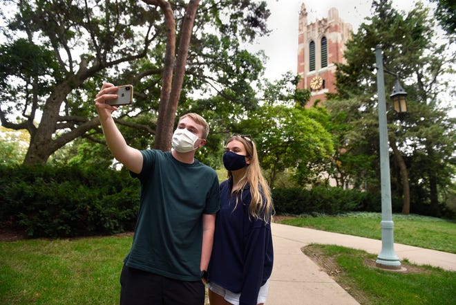 MSU freshmen Noah Scudder, left, of Troy, and Amelia Nevelos, right, of Northville, take a picture near Beaumont Tower on campus in East Lansing as they visit campus Saturday. The two students are both taking remote classes from MSU and living at home.