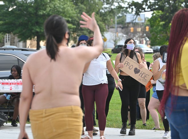 A shirtless woman gestures to friends at the 2020 Detroit Slutwalk  held at Palmer Park on Saturday, September 12, 2020.
