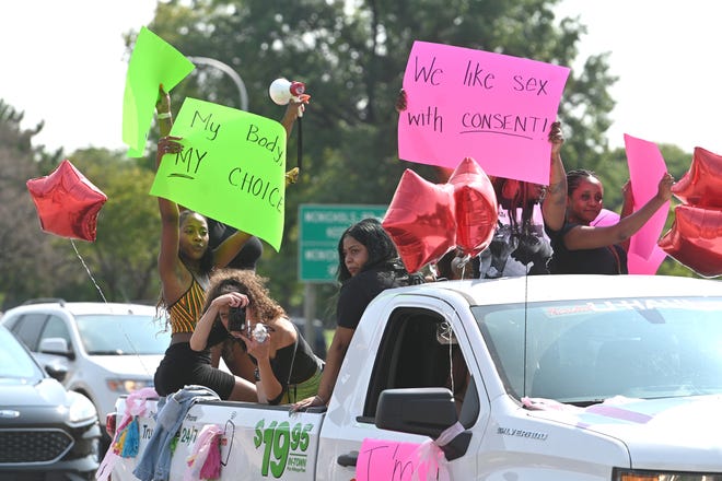 Participants ride in the bed of a pickup along Woodward Avenue near State Fair during the 2020 Detroit Slutwalk .