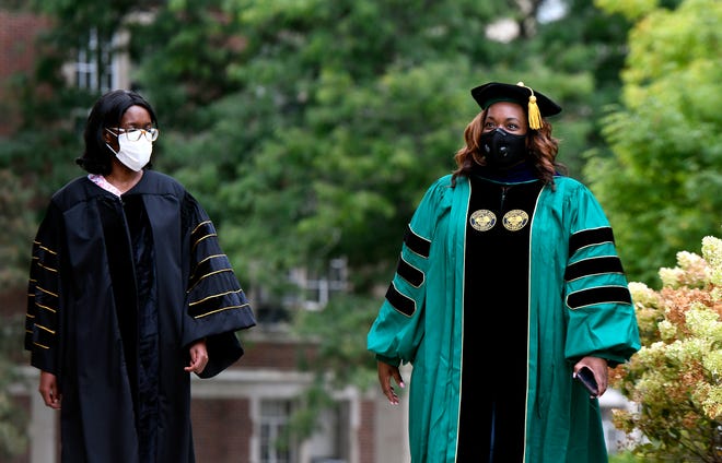 Recent Michigan State doctorate graduates Leah Mungai, left, and Dee Jordan wore protective masks while having their photos taken in the graduation robes in September.