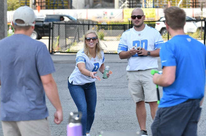 From left, Brandon Fiting, 29, Teresa Fiting, 26, both of Clawson, Jason Collison, 27, of Royal Oak and Cameron Fauver, 26, of Royal Oak play washers in a parking lot near Comerica Park.  Detroit Lions vs Chicago Bears at Ford Field in Detroit on Sept. 13, 2020.