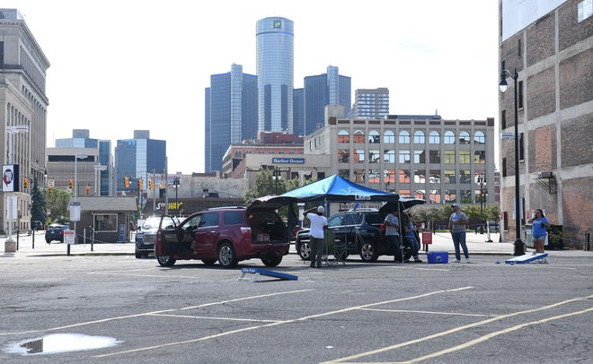 A group tailgates in an almost empty parking lot that is usually packed with Lions fans.  Detroit Lions vs Chicago Bears at Ford Field in Detroit on Sept. 13, 2020.
