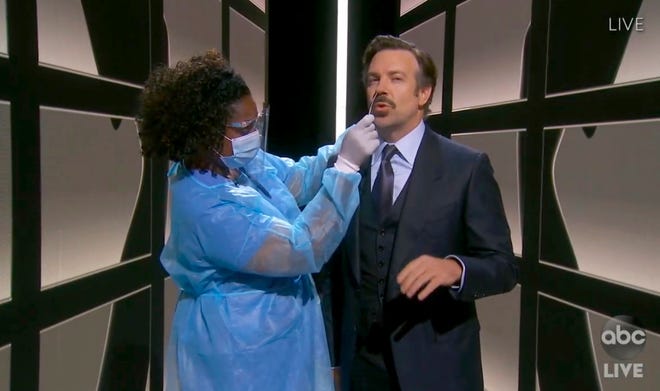 In this video grab captured on Sept. 20, 2020, courtesy of the Academy of Television Arts & Sciences and ABC Entertainment, Jason Sudeikis, right, gets a COVID-19 test as he presents the award for outstanding comedy series during the 72nd Emmy Awards broadcast.
