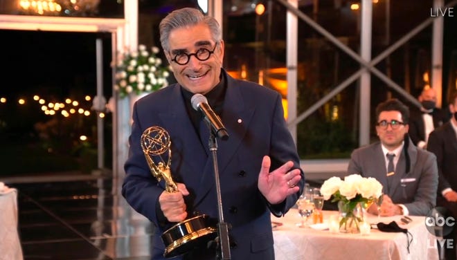 In this video grab captured on Sept. 20, 2020, courtesy of the Academy of Television Arts & Sciences and ABC Entertainment, Eugene Levy accepts the outstanding lead actor in a comedy series award for "Schitt's Creek" as his son and castmate Dan Levy looks on at right during the 72nd Emmy Awards broadcast.