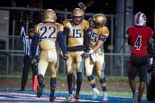 Rochester Hills Stoney Creek running back Camron Burford (22) quarterback Jacob Best (15) and tight end Cole Luhmann (35) celebrate a touchdown during the first quarter.