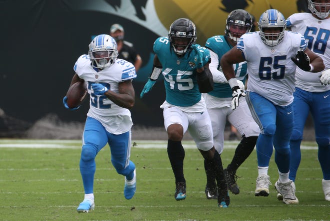 Lions running back D'Andre Swift (32) runs past Jaguars linebacker K'Lavon Chaisson (45) during the first half of an NFL football game on Sunday, Oct. 18, 2020, in Jacksonville, Fla.