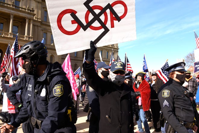 State police escort a counter demonstrator away from President Donald Trump enthusiasts  as Trump supporters gather at the state Capitol Building  in Lansing for a "Stop the Steal" rally disputing the presidential voting Saturday, October 14, 2020.