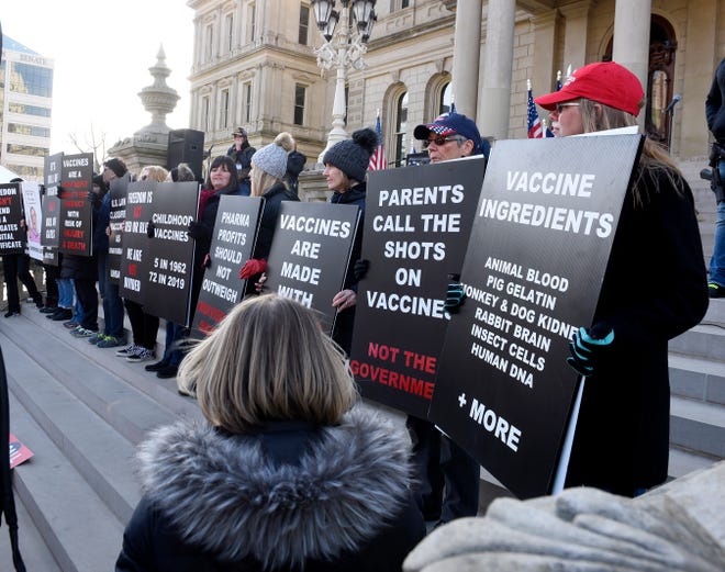 Women hold up signs regarding vaccines as  President Donald Trump supporters gather at the state Capitol Building  in Lansing for a "Stop the Steal" rally disputing the presidential voting Saturday, October 14, 2020.