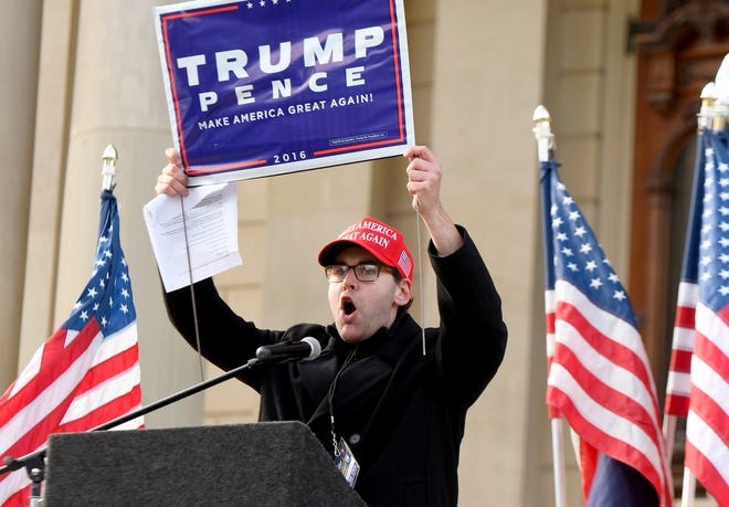 Speaker Brandon Hall holds up a Trump/Pence sign as he speaks to President Donald Trump supporters gathered at the state Capitol Building  in Lansing for a "Stop the Steal" rally disputing the presidential voting Saturday, October 14, 2020.