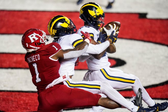 Michigan's Daxton Hill, right, intercepts a pass intended for Rutgers' Isaih Pacheco, left, as Michigan's Vincent Gray, center, defends during the third overtime.