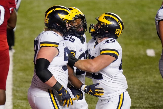 Michigan's Hassan Haskins (25) celebrates with Karsen Barnhart, left, and Ben Mason during the third overtime.