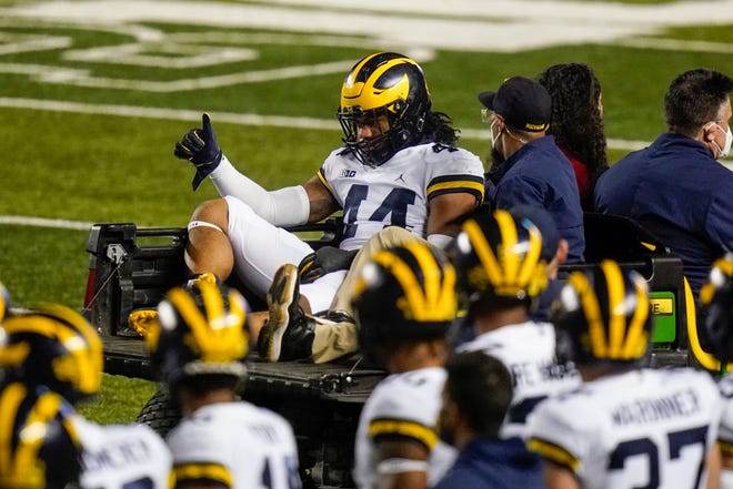 Michigan's Cameron McGrone (44) gestures to teammates as he is carted off the field after being injured during the first half.