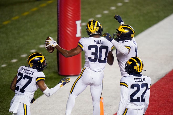 Michigan's Daxton Hill (30) celebrates with Josh Ross (12), Gemon Green (22) and Hunter Reynolds after his interception during the third overtime.