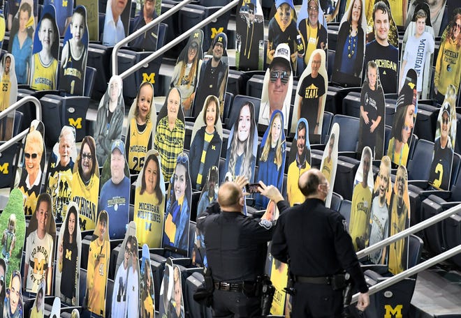 A University of Michigan police officer takes a photo of the cutout fans before the game.  Michigan vs Minnesota at Crisler Center in Ann Arbor, Mich. on Jan. 6, 2021.