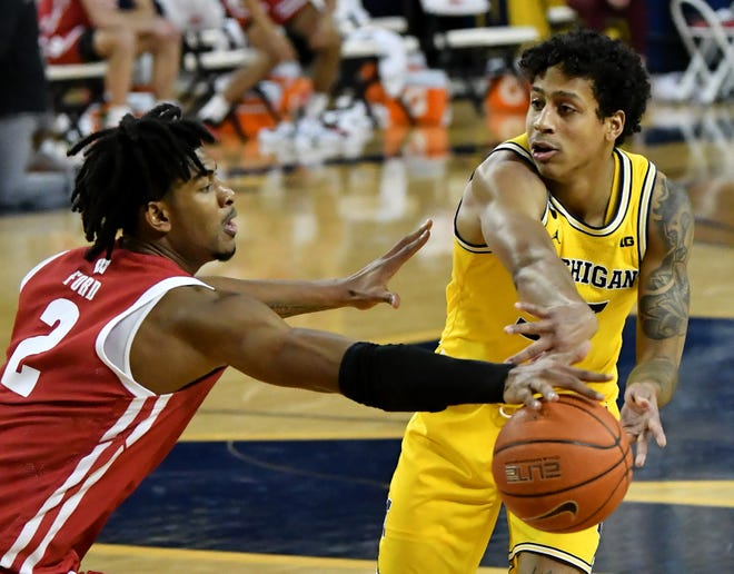 Wisconsin forward Aleem Ford (2) reaches in to try and steal the ball from Michigan guard Eli Brooks (55) in the second half.  Michigan vs Wisconsin at Crisler Center in Ann Arbor, Mich. on Jan. 12, 2021.  Michigan wins, 77-54.