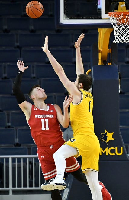 Michigan center Hunter Dickinson (1) defends a shot by Wisconsin forward Micah Potter (11) in the first half.