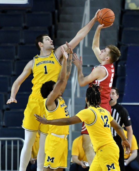 Michigan center Hunter Dickinson (1) blocks a shot by Wisconsin forward Tyler Wahl (5) with Michigan's Eli Brooks (55) and Mike Smith (12) helping out in the first half.