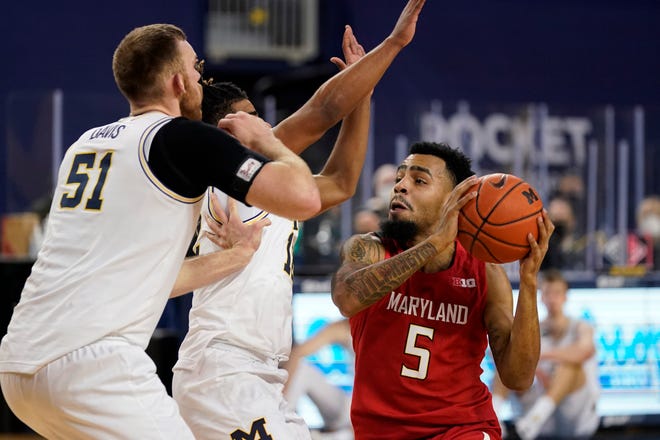 Maryland guard Eric Ayala (5) is defended by Michigan forward Austin Davis (51) and guard Mike Smith (12) during the first half.