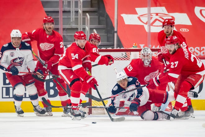 The two teams battle for the puck in the first period of a game between the Detroit Red Wings and the Columbus Blue Jackets.